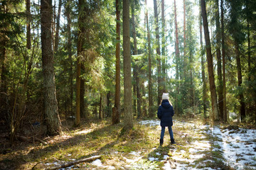 Obraz premium Cute young girl having fun during forest hike on beautiful winter day. Active family leisure with kids.