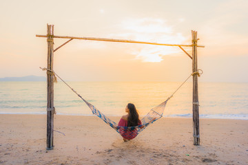 Portrait beautiful young asian woman sitting on the hammock with smile happy neary beach sea and ocean