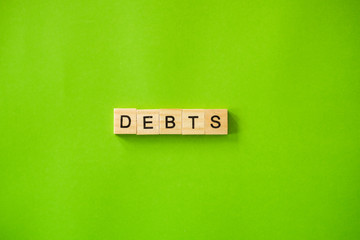 The word DEBTS shot flat lay on a green isolated background