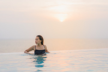 Portrait beautiful young asian woman happy smile relax around swimming pool in hotel resort