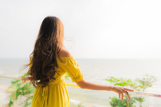 Portrait beautiful young asian woman smile happy and relax at outdoor balcony with sea beach and ocean view