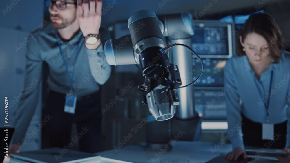 Poster futuristic metal robotic arm picking up a metal object and moving it. senior engineer talks through 