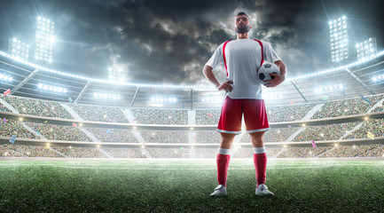 Night stadium panorama. Soccer player holds a soccer ball. Sport concept. Mockup