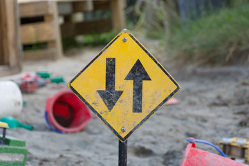 Two way road sign in a playground sandpit