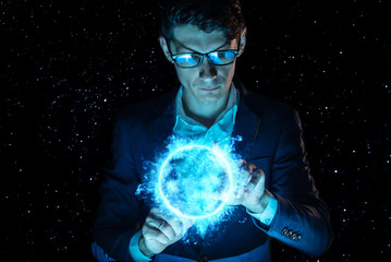 Man businessman holding hands over a blue glowing plasma sphere. Magic prediction and foresight in...