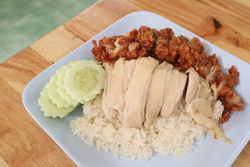 Hainanese chicken rice with Roasted Chicken on wooden table.Hainanese chicken rice is a dish of poached chicken and seasoned rice, served with chili sauce