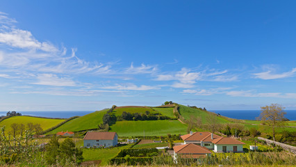 Fototapeta na wymiar Countryside landscape of Sao Miguel Island in Azores, Portugal. Hilly landscape with fields, meadows and Atlantic Ocean to horizon.