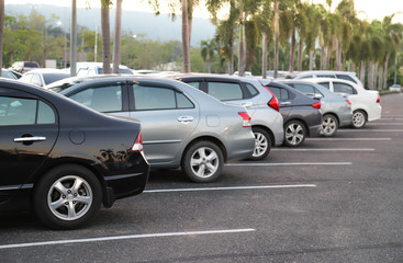 Closeup of rear or back side of black car with  other cars parking in parking area with natural background in twilight evening. 