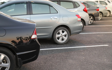 Closeup of rear or back side of black car with  other cars parking in outdoor parking area in twilight evening. 