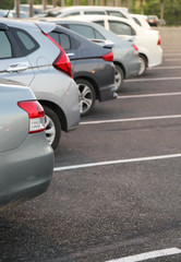 Closeup of back or rear side of green blue car with  other cars parking in parking area in twilight evening.  Vertical view. 