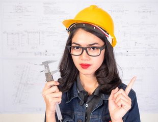 Female engineer holding a measuring instrument With a blueprint as a backdrop