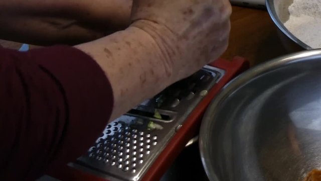 elderly woman grating a zukini
