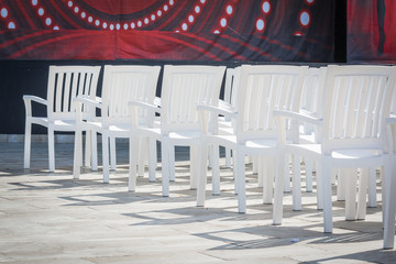 White simple chairs with back in summer theater for viewing performances on stage.