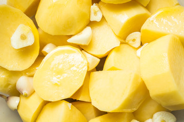Uncooked garlic potatoes for pickling in deep dish.