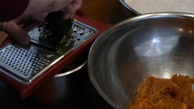 grating zukini into a silver bowl