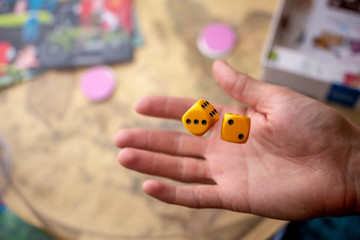 The hand throws two yellow dice on the playing field. The concept of Board games. Gaming moments in dynamics