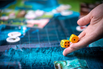 Fototapeta premium Hand throws two yellow dice on the blue field of the fantasy game. Gaming moments in dynamics. Board games strategy