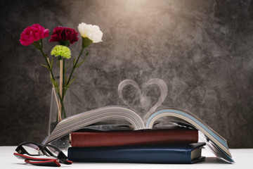 Love story book with open page of literature in heart shape and glasses