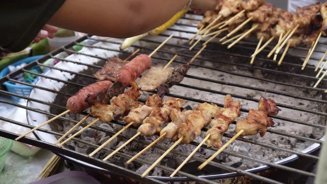 Close up hand making grilled pork/beef barbecue, Thai street food, Bangkok, Thailand