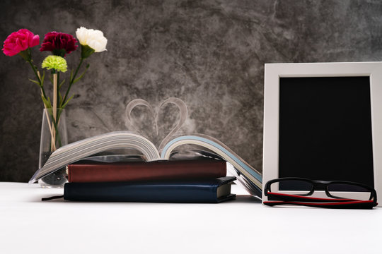 Love story book with open page of literature in heart shape and photo frame for writing space