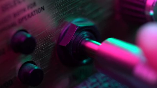 Man connects the jack to the amp. Colorful neon light. Close up view. Concert, music concept