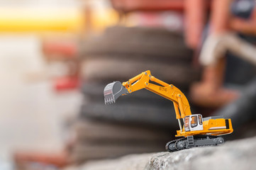 Fototapeta premium yellow excavator model toy parked on floor ground on a construction site background. (image stacking technique)