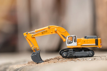 Yellow excavator model toy performs excavation work on a construction site. (Image stacking...