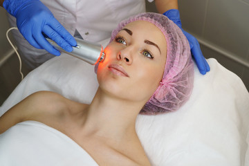 Obraz na płótnie Canvas Hardware cosmetology. Ultrasound chromotherapy. Beautician carries out procedure for tightening skin of face. Spa. Non-surgical cosmetology. Skin peeling