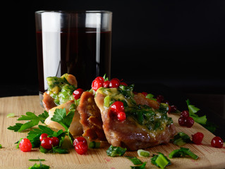 Wild fresh meat with greens and berries and wine. Meat on a wooden board.