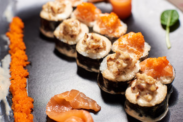 Close up of tasty fresh sushi rolls with fish and rice on black plate. Sushi rolls served on a wooden table in a restaurant