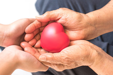 Philanthropy health care concept. Caregiver with senior people hands with heart in palm in hospice...