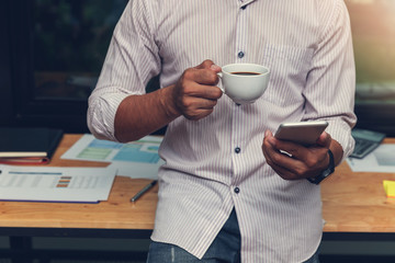 Business and finance concept of office working, Businessman using smartphone and holding coffee cup in office