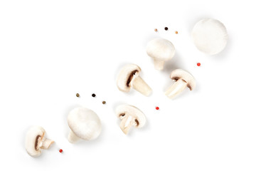 Champignon mushrooms, whole and sliced, shot from the top on a white background with peppercorns, a flat lay composition with copy space