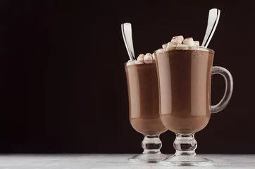 Foto op Aluminium Elegance hot chocolate in two classic irish coffee glass with marshmallows and silver spoons on dark brown wall and white wooden table, copy space. © finepoints
