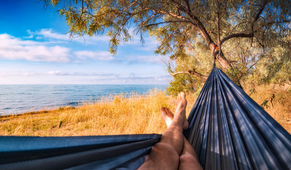 Man lays in a hammock on a sea beach