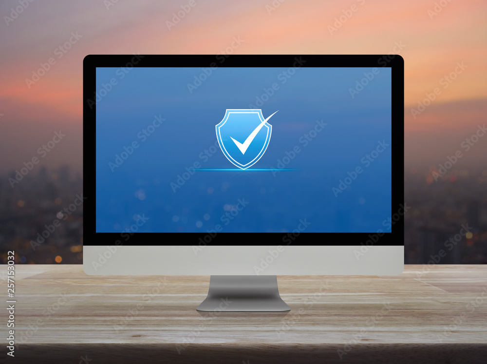 Poster security shield with check mark icon on desktop modern computer monitor screen on wooden table over 