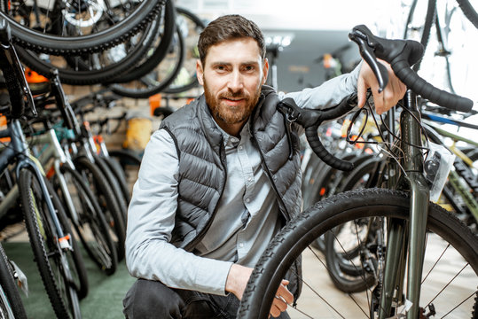 Portrait of a handsome man as a buyer or salesperson with bicycle at the bicycle store
