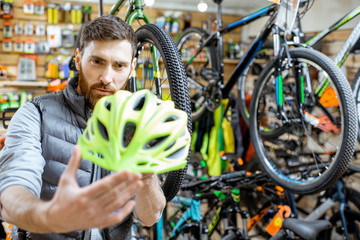 Man checking the quality of a new protective helmet standing in the bicycle shop