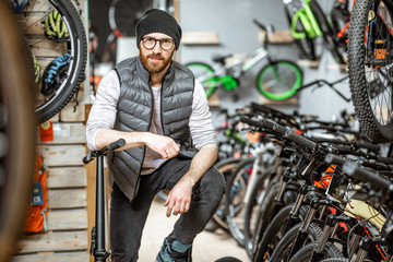Fototapeta na wymiar Portrait of a stylish man with folding bicycle at the bicycle shop