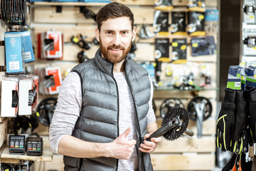 Portrait of a handsome salesman standing at the bicycle shop with bicycle parts on the background