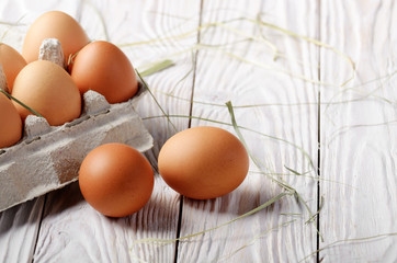Raw organic brown chicken eggs in eco friendly paper carton on white kitchen wooden table