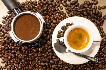Cup of espresso coffee and portafilter on coffee beans background ,fresh espresso with crema (perfect shot) in the morning at cafe shop,top view