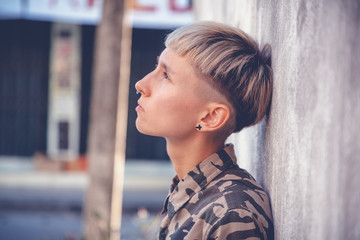 Stylish brutal young woman with short hair and shaved temples with a smartphone   background of ...
