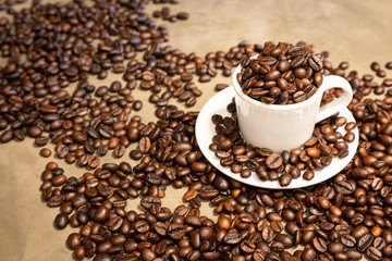 Roasted coffee beans in a cup of hot espresso,arabica beans and robusta beans mixed,medium roasted to dark roasted on cement background in a cafe shop,for espresso drink in the morning, copy space