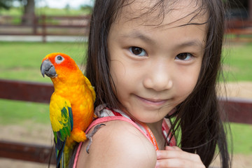 Asian girl has a parrot perched on her shoulder,child happy with the bird in the zoo