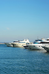 Fototapeta na wymiar Many white yachts on the wharf. Elegant yachts on the background of the blue sky.