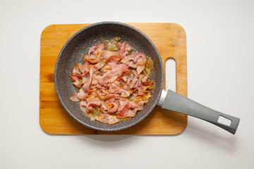 frying pan with fried bacon and onion