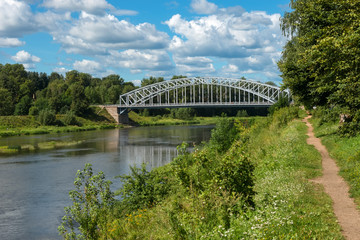 First in Russia steel arch bridge on river Msta in sunny summer day. Novgorod region, Borovichi, Russia. Was built in 1905.