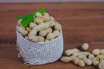 Peanuts in basket on wood background