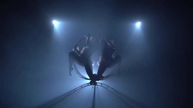 Spin on the stage professional gymnasts . Black smoke background. Silhouette